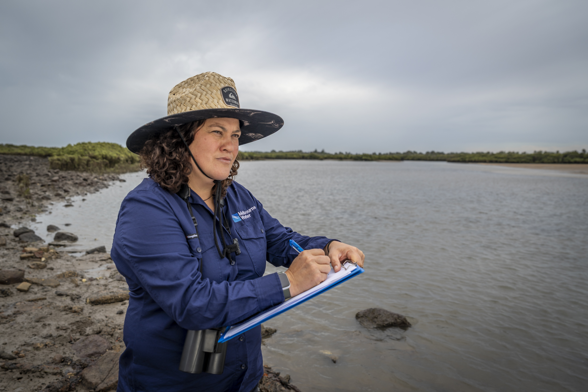 A woman standing with a notepad near water