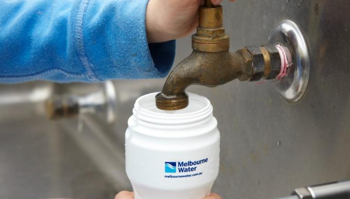 A young person fills up a Melbourne Water branded water bottle at a tap