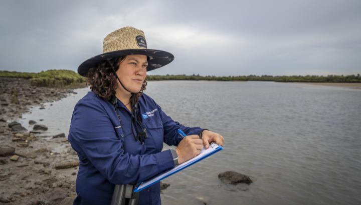 A woman standing with a notepad near water