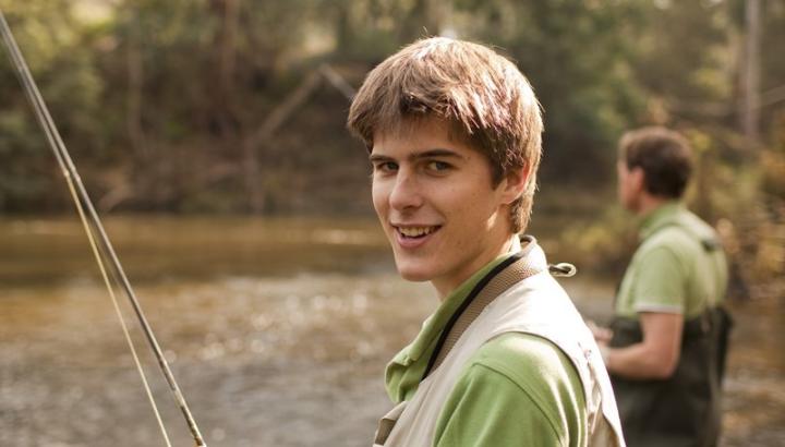 Boy and man fishing by a river