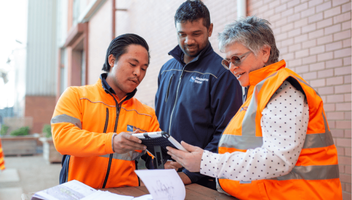 Three diverse people standing outside having a conversation over a device screen