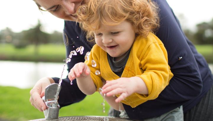 A woman and her child drink from a public water fountain