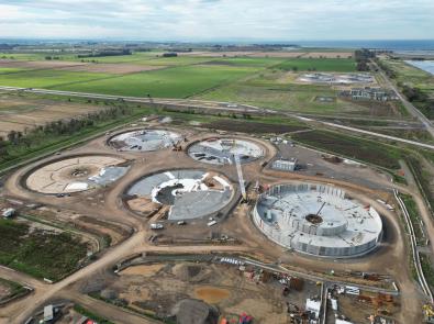 Caption – Aerial photo of the 5 tanks being constructed. There is varying levels of progress of each tank and cranes in action.  