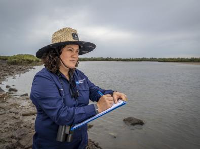 A woman standing with a notepad near water