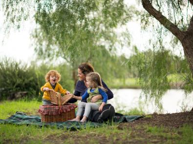 Mother and children having a picnic by their local waterway