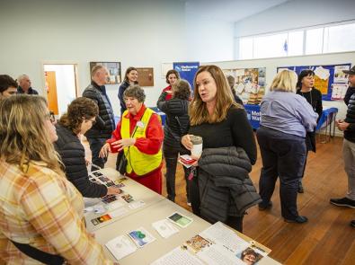 Community gathering at information table in hall.