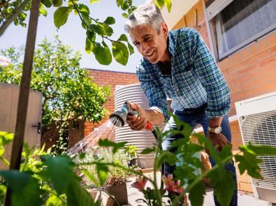 Man watering his vegetable garden with a trigger nozzle hose