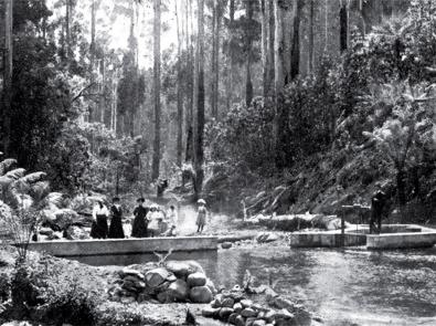 Black and white historic photo of women standing on a weir