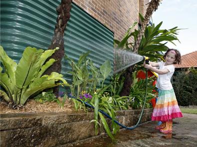 Rainwater tank and girl with a garden hose