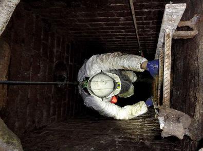 Worker descending into a sewer via a ladder