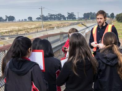 Group of school children stand next to concrete channel at the Western Treatment Plant