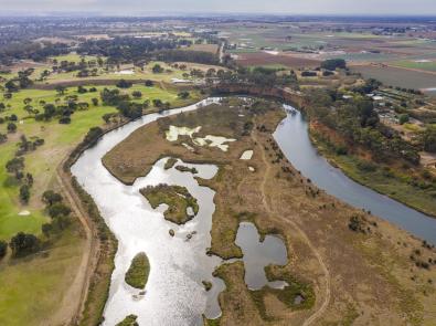 The Werribee River winds its way through flat plains, including agricultural land.