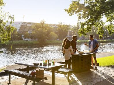 Group of people at barbecue by the Yarra River, opposite the MCG