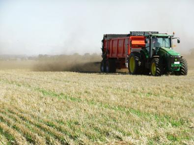 Truck spreading dirt-like biosolids on farmland