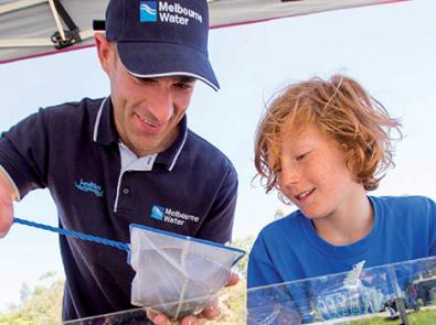 Melbourne Water worker showing young boy item from waterway