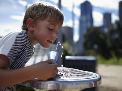 Boy outdoors drinking from a water fountain