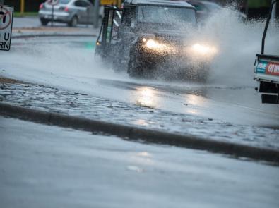 Car drives through puddle of stormwater on road