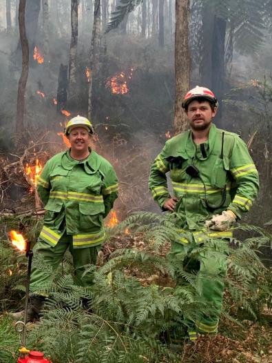 two firefighters with flames behind them