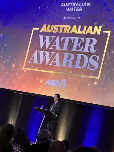 Australian Water Awards A person giving a speech with a presentation behind them reading "Australian Water Awards"