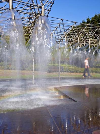 People walking through public water fountain