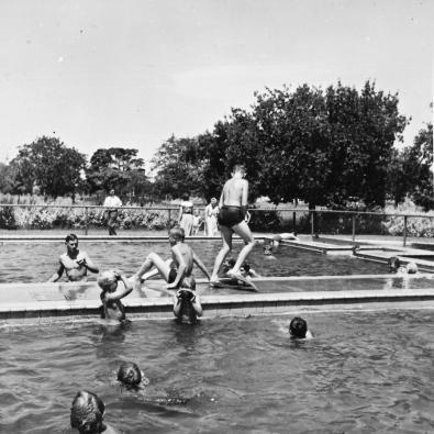 Black and white photo of children playing in outdoor pool