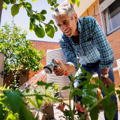 Man watering his vegetable garden with a trigger nozzle hose