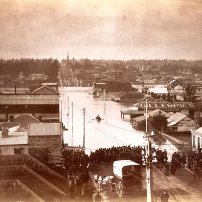 Sepia photograph of half-submerged houses in flooded river