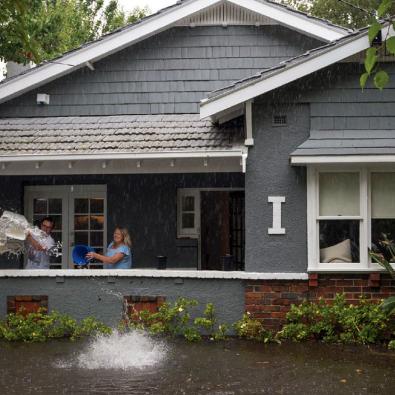 Man and woman bail out flooded home with buckets