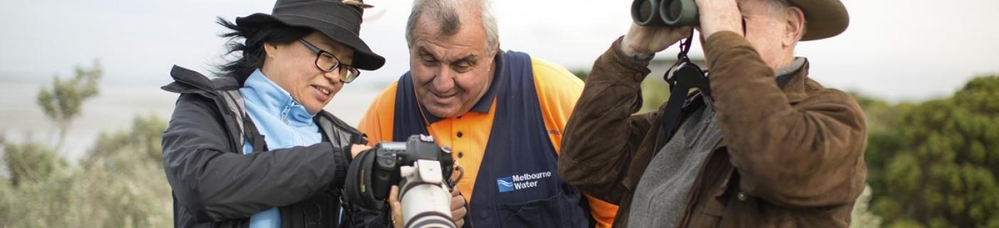 Melbourne Water employee and two people with binoculars