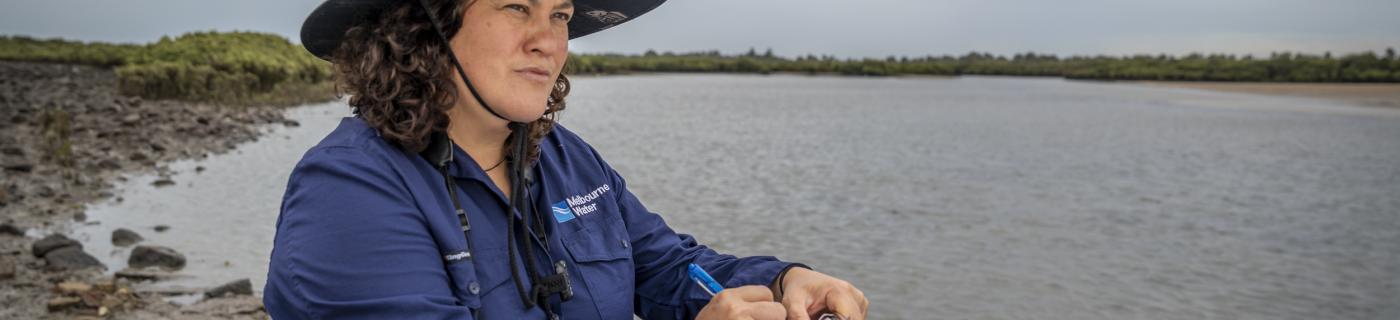 A woman standing with a notepad near water