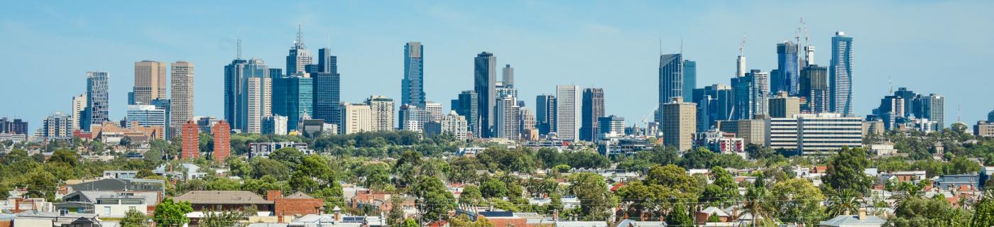 Melbourne city skyline with brick houses and trees in the foreground