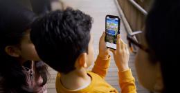 Boy holds smartphone with "Litter Critters" on the screen