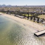 Aerial view of Port Phillip Bay with Elwood Pier in the foreground and the Melbourne CBD in the background.