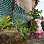 Rainwater tank and girl with a garden hose