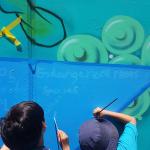 Two children painting an endangered frog mural