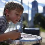 Boy outdoors drinking from a water fountain