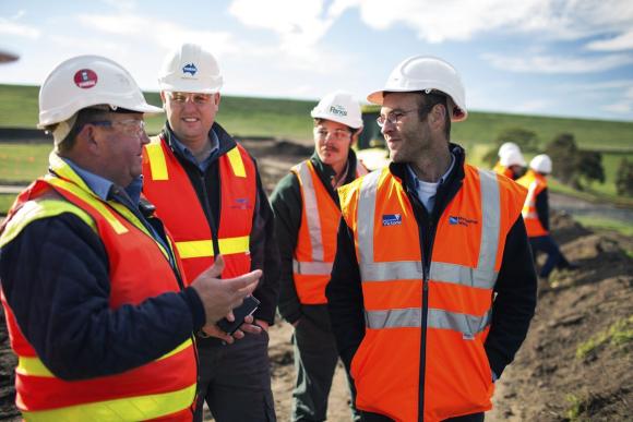 Workers in high visibility vests and hard hats talking at a project site