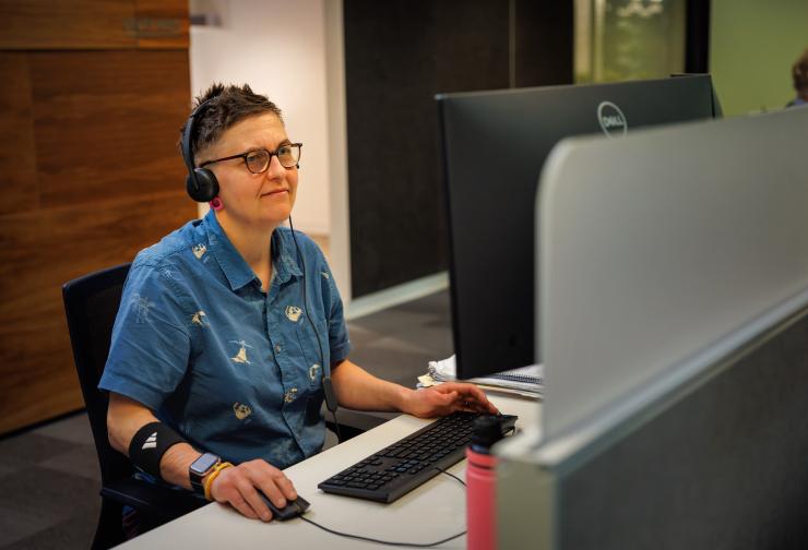 Person sitting at desk working on the computer with telephone headset on