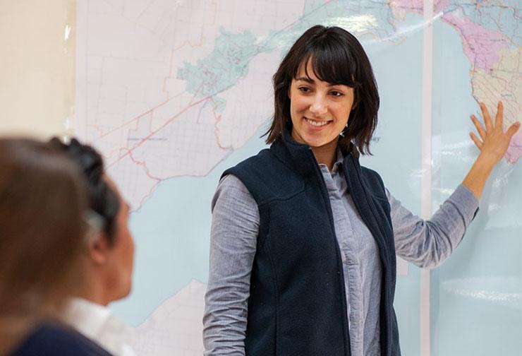 Woman presents map in front of seated audience