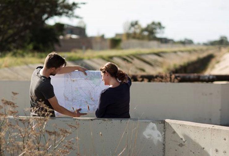 Two people look at plans while standing over an easement