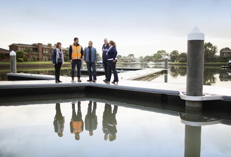 Melbourne Water worker and customers standing by the water on a jetty