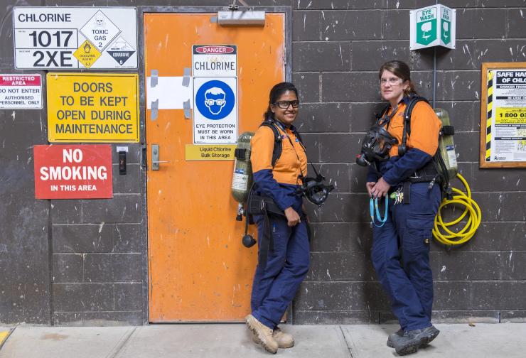 Two women standing in front of an orange door and safety signs