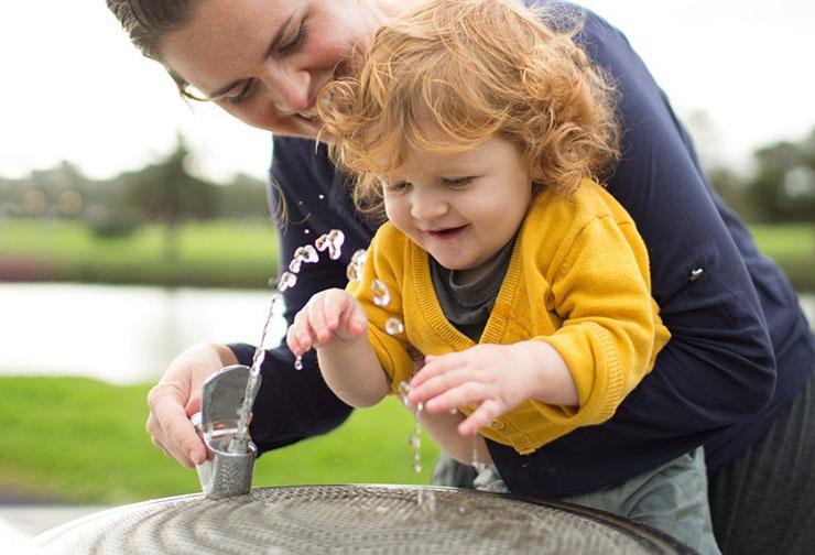 Woman and child at outdoor drinking water fountain