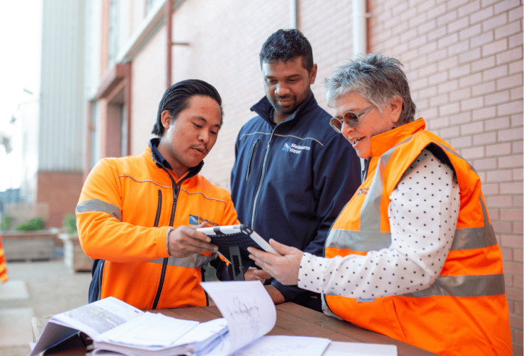 Three diverse people standing outside having a conversation over a device screen