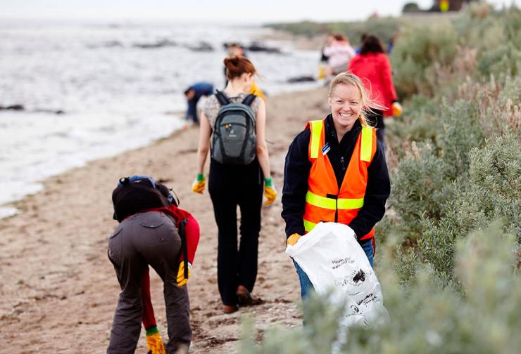 People collect rubbish along the bay as part of a community event