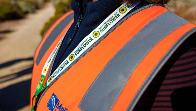 Close up of person wearing a sunflower lanyard and a Melbourne Water safety vest