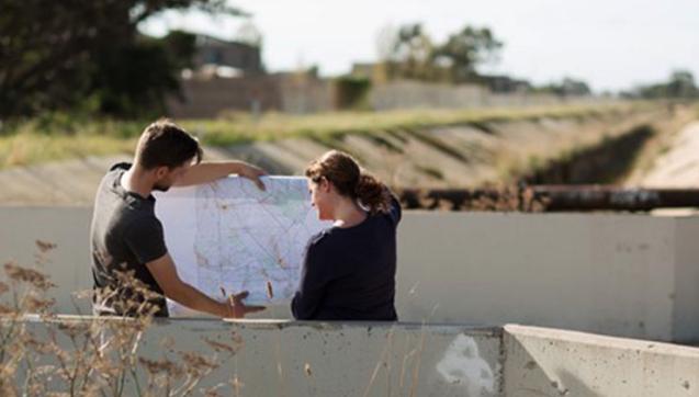 Two people look at plans while standing over an easement