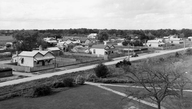 Black and white photograph of rows of weatherboard houses on a grassy land