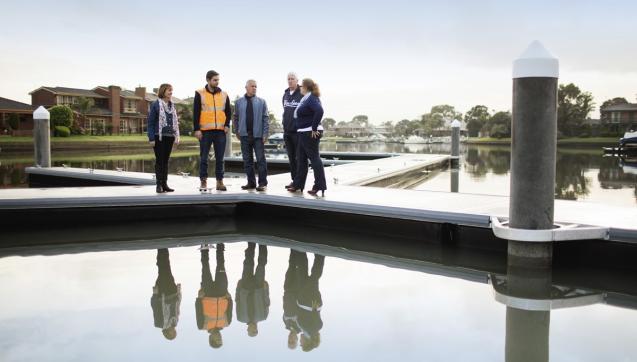 Melbourne Water worker and customers standing by the water on a jetty