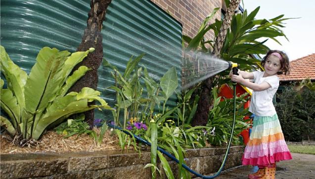 Rainwater tank and girl with a garden hose